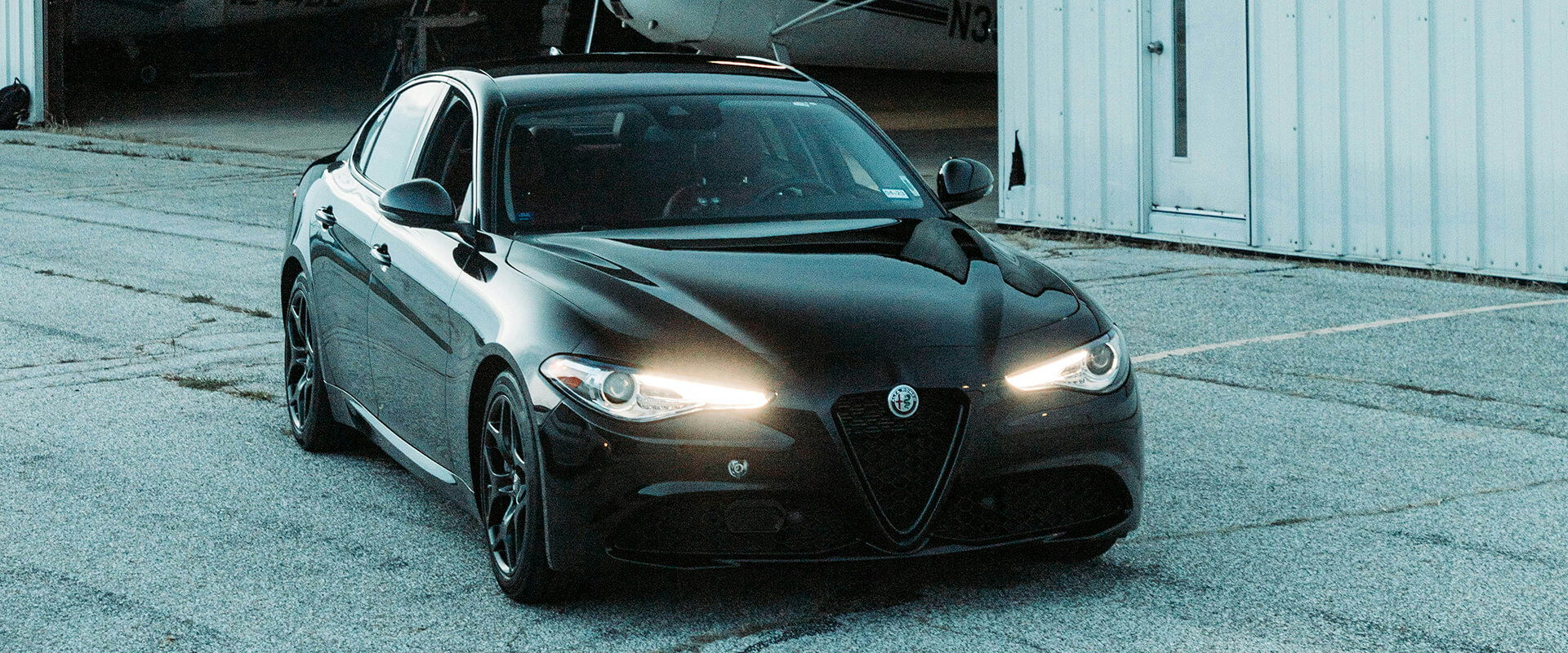 Black luxury car parked near white building.