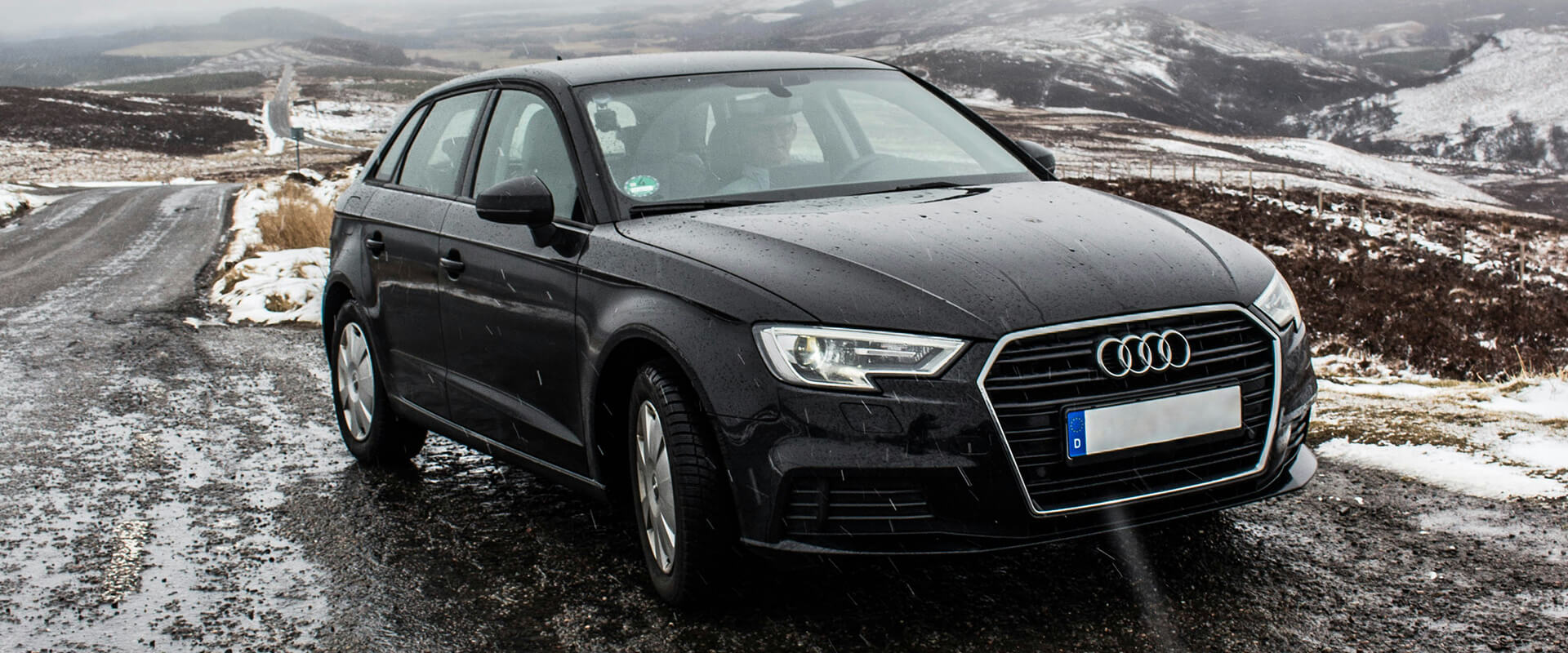 Black car on snowy mountainous road